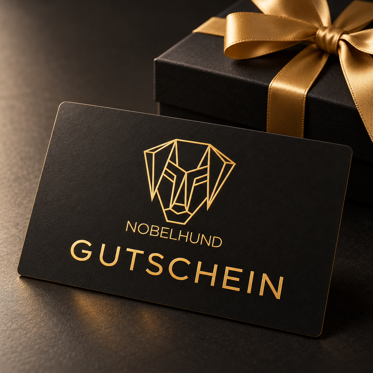 NOBELHUND-Gutschein in Schwarz und Gold vor einer Geschenkbox mit goldener Schleife.